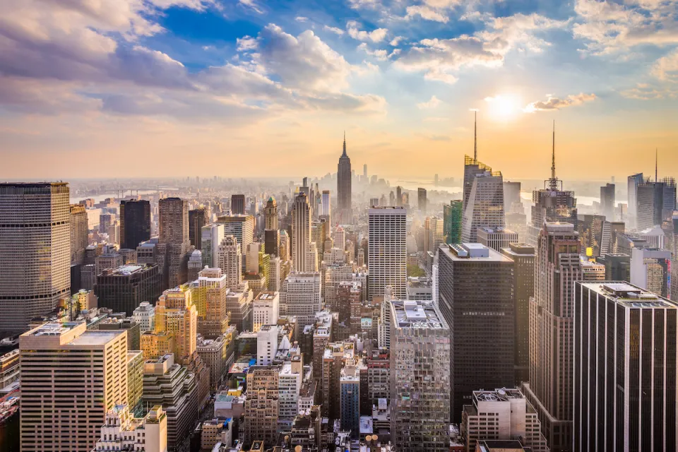 New York City skyline with Empire State Building in center and blue cloudy sky.